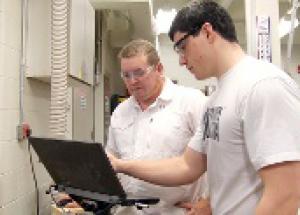 Students working on the computer controlling the CNC router